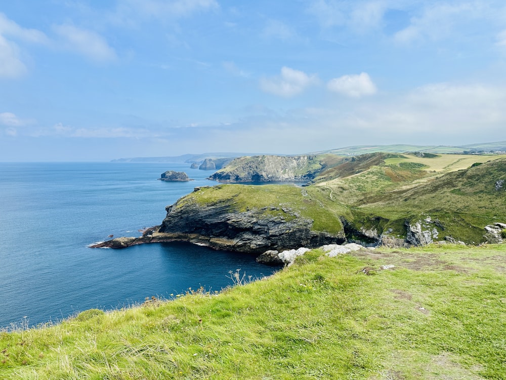 a grassy hill with a body of water in the background