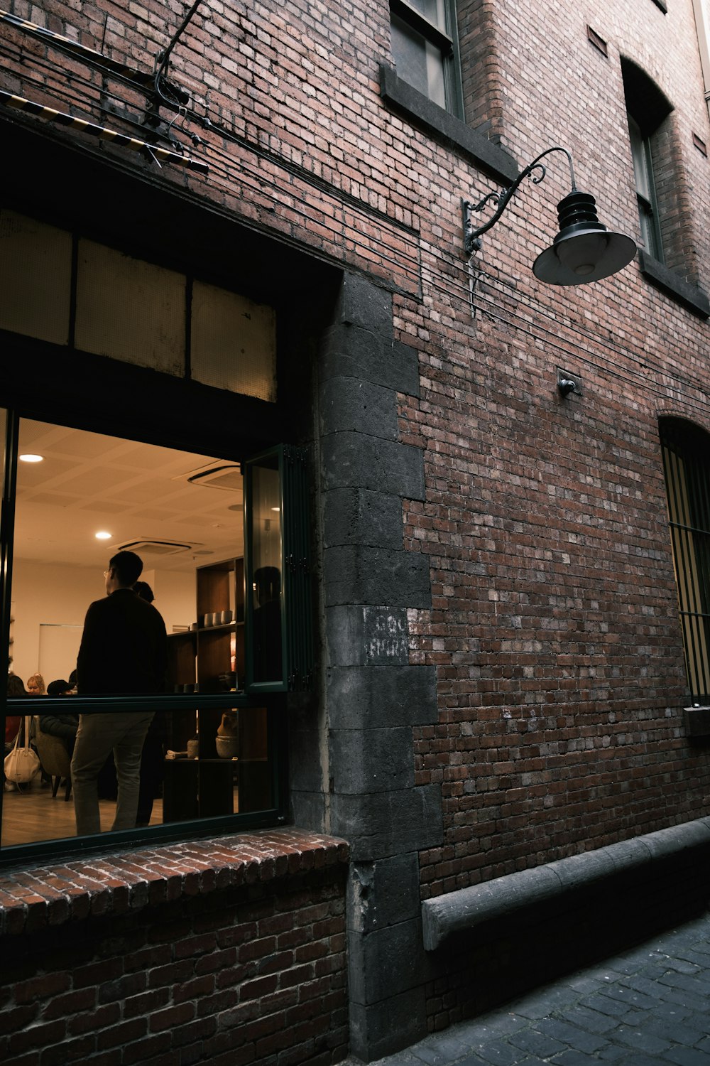 a man standing in a window of a brick building