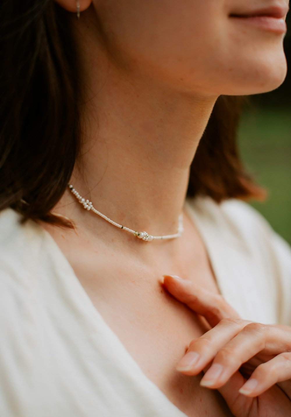 a woman in a white shirt is wearing a necklace