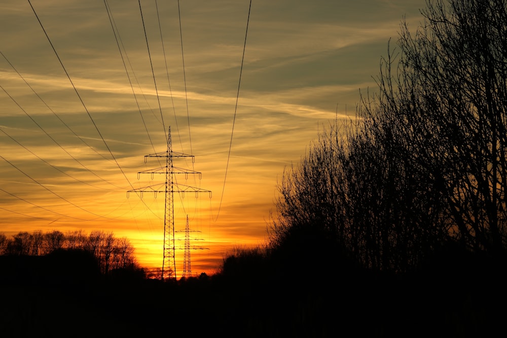 the sun is setting behind the power lines