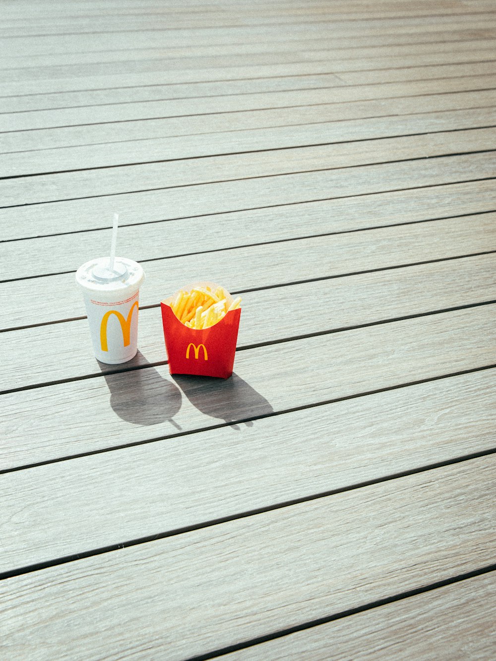 a hot dog and a cup of mcdonald's on a wooden deck