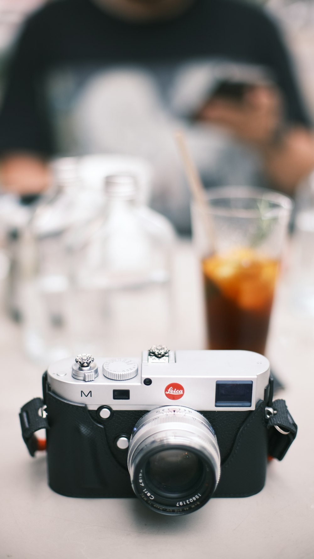 uma câmera sentada em cima de uma mesa ao lado de um copo