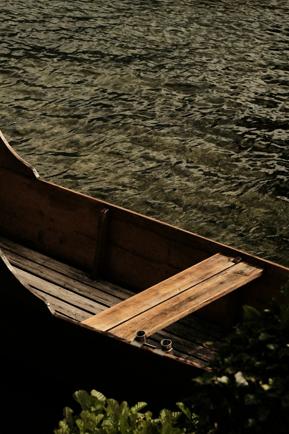 um pequeno barco de madeira flutuando em cima de um corpo de água