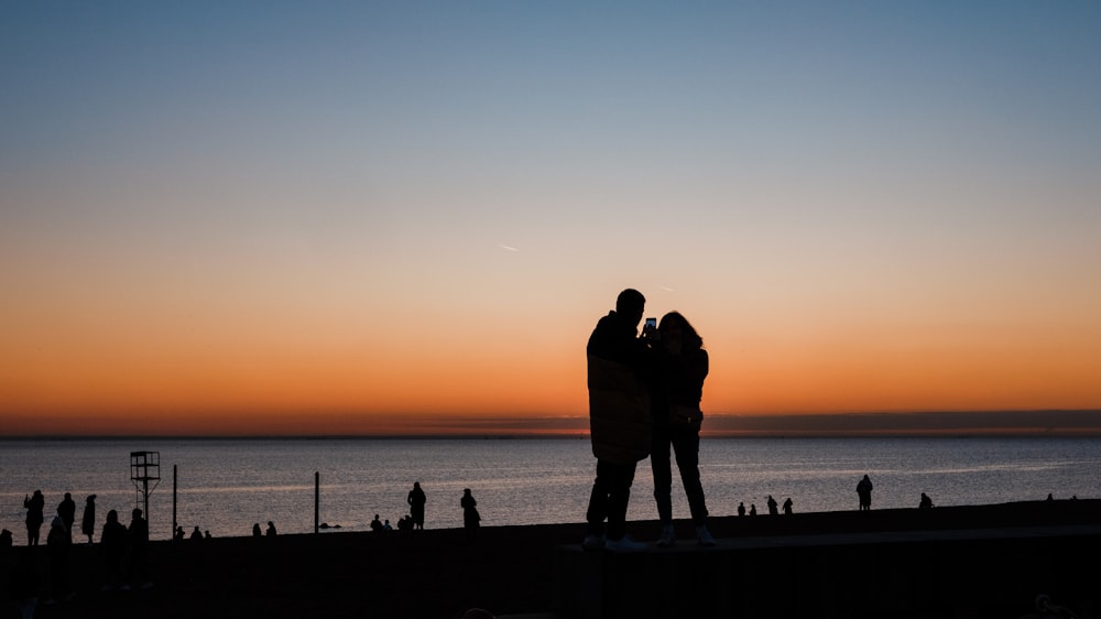 a couple of people standing next to each other near a body of water