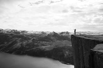 Close-up black and white photo of a verticalvoid member wearing a medal with a subtle mention of a French record, set against rocky Pyrenean cliffs.