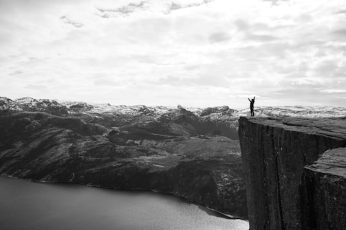 Close-up black and white photo of a verticalvoid member wearing a medal with a subtle mention of a French record, set against rocky Pyrenean cliffs.
