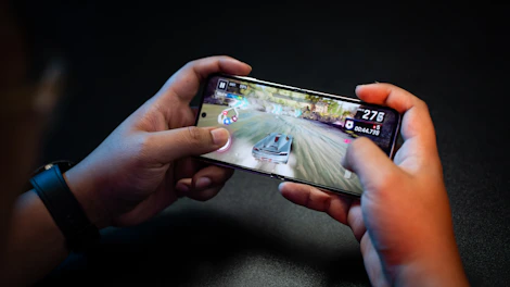 Close-up of hands holding a phone with a popular Android game on screen.