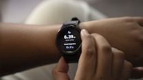 A person is adjusting a smartwatch on their wrist with their other hand. The smartwatch screen displays the current time, sleep duration, and includes a moon icon, possibly indicating sleep tracking.