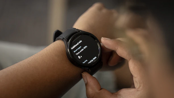 Modern smartwatch with health monitoring apps open, showing blood oxygen and activity rings on the screen.