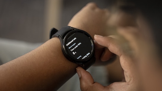 A person is wearing a smartwatch on their wrist, with the display showing health-related information such as blood oxygen levels and time under 90%. The person is interacting with the watch, touching the screen with their fingers.