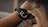 A person is wearing a smartwatch on their wrist, with the display showing health-related information such as blood oxygen levels and time under 90%. The person is interacting with the watch, touching the screen with their fingers.