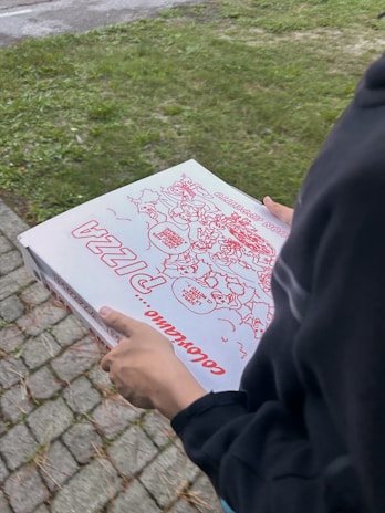 A happy customer holding a pizza box outside the NYC Pizza shop on a bustling city street.