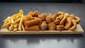 A colorful platter of assorted fried foods including wings, shrimp, and fries.