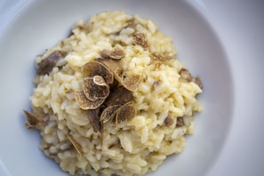 A rich bowl of creamy risotto garnished with fresh parsley and shaved truffle