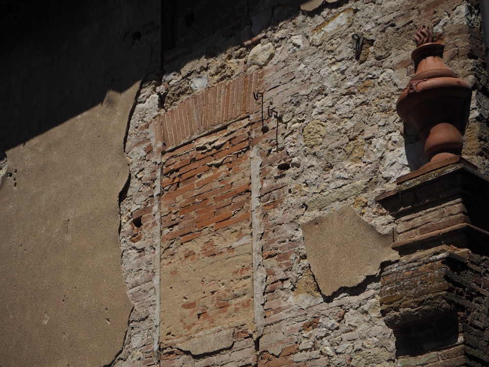 a brick wall with a window and a vase on top of it