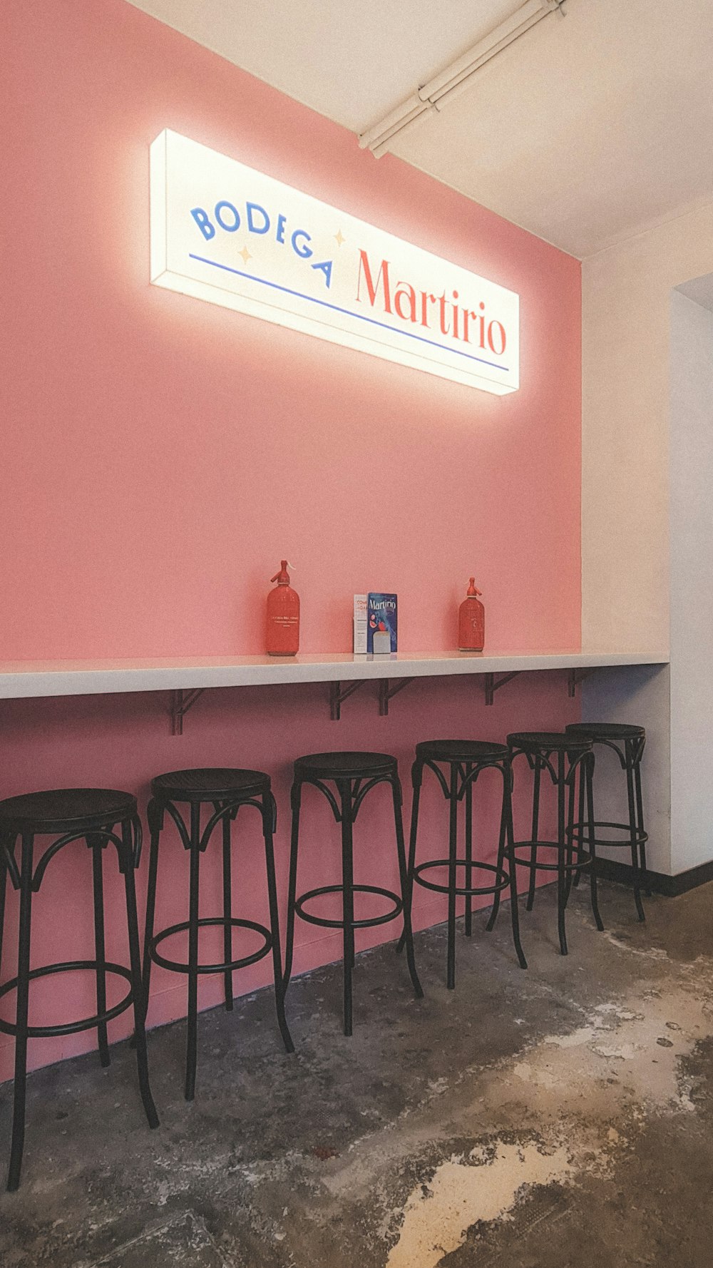 a row of bar stools in front of a pink wall