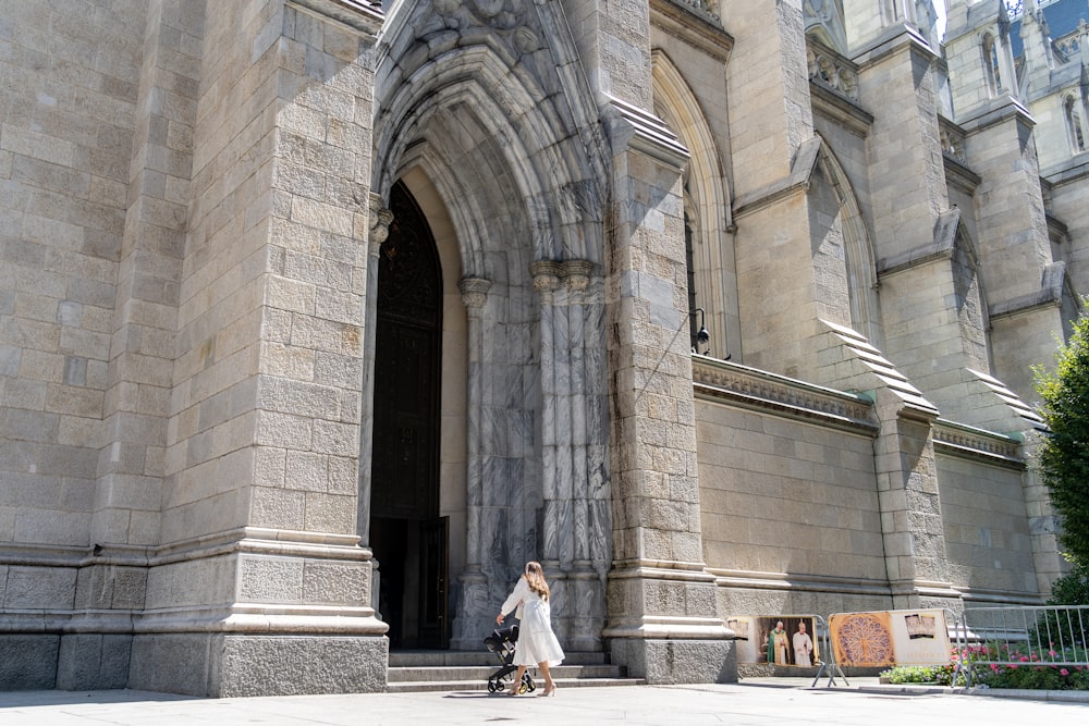 a woman walking down a street past a tall building