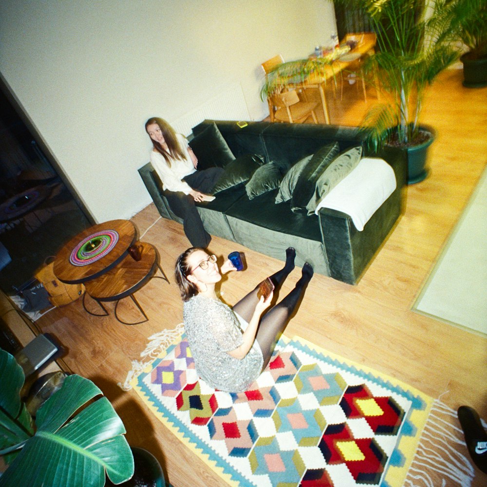 two women sitting on a rug in a living room