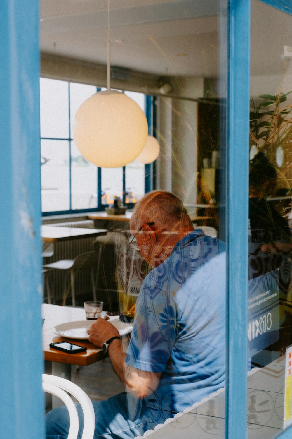 a man sitting at a table in front of a window