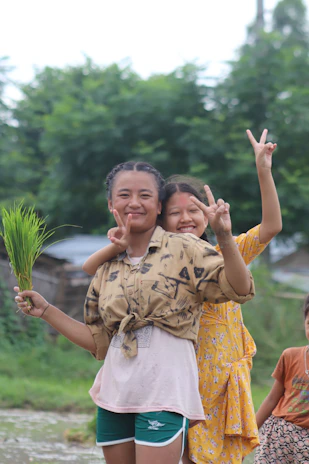 Happy farmer couple smiling while holding baskets of vibrant produce in front of a greenhouse.