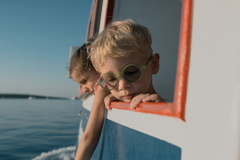 a couple of kids on a boat looking out the window