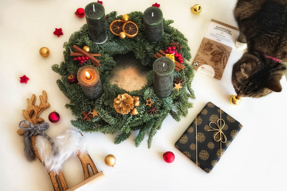 a cat sitting next to a christmas wreath