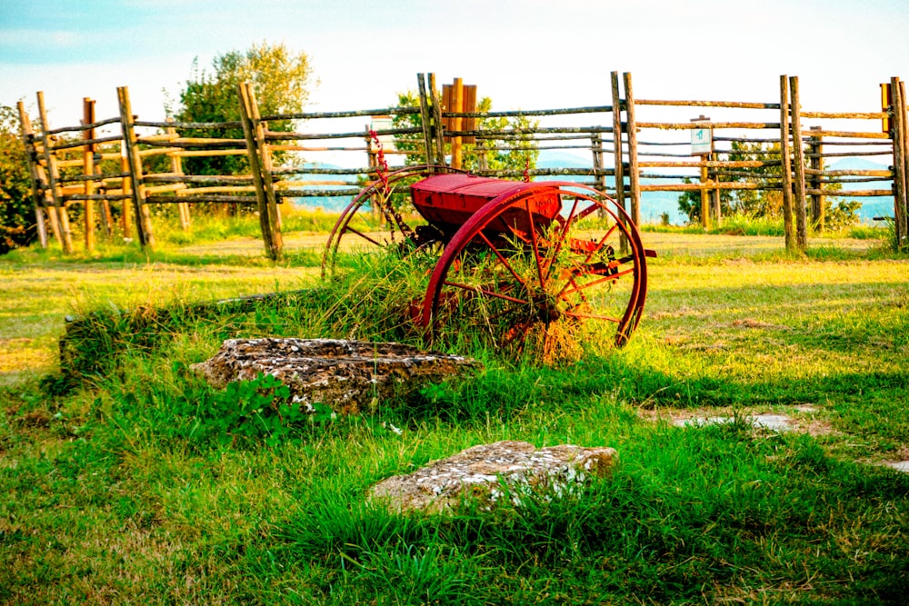 a red wagon sitting on top of a lush green field