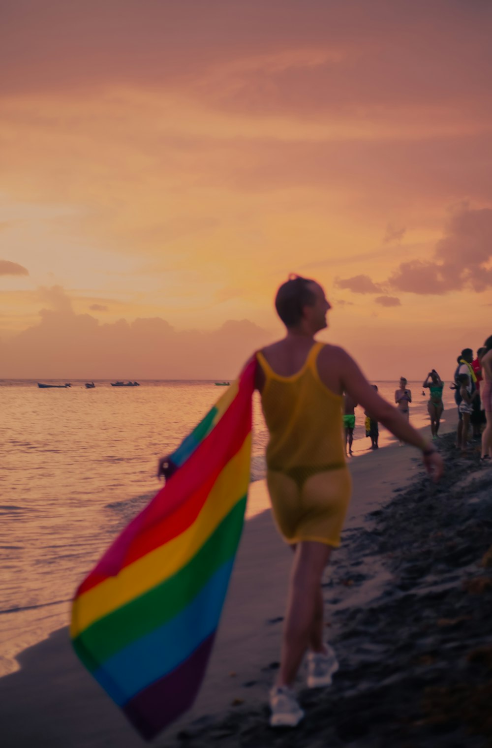 a person walking on a beach holding a rainbow flag