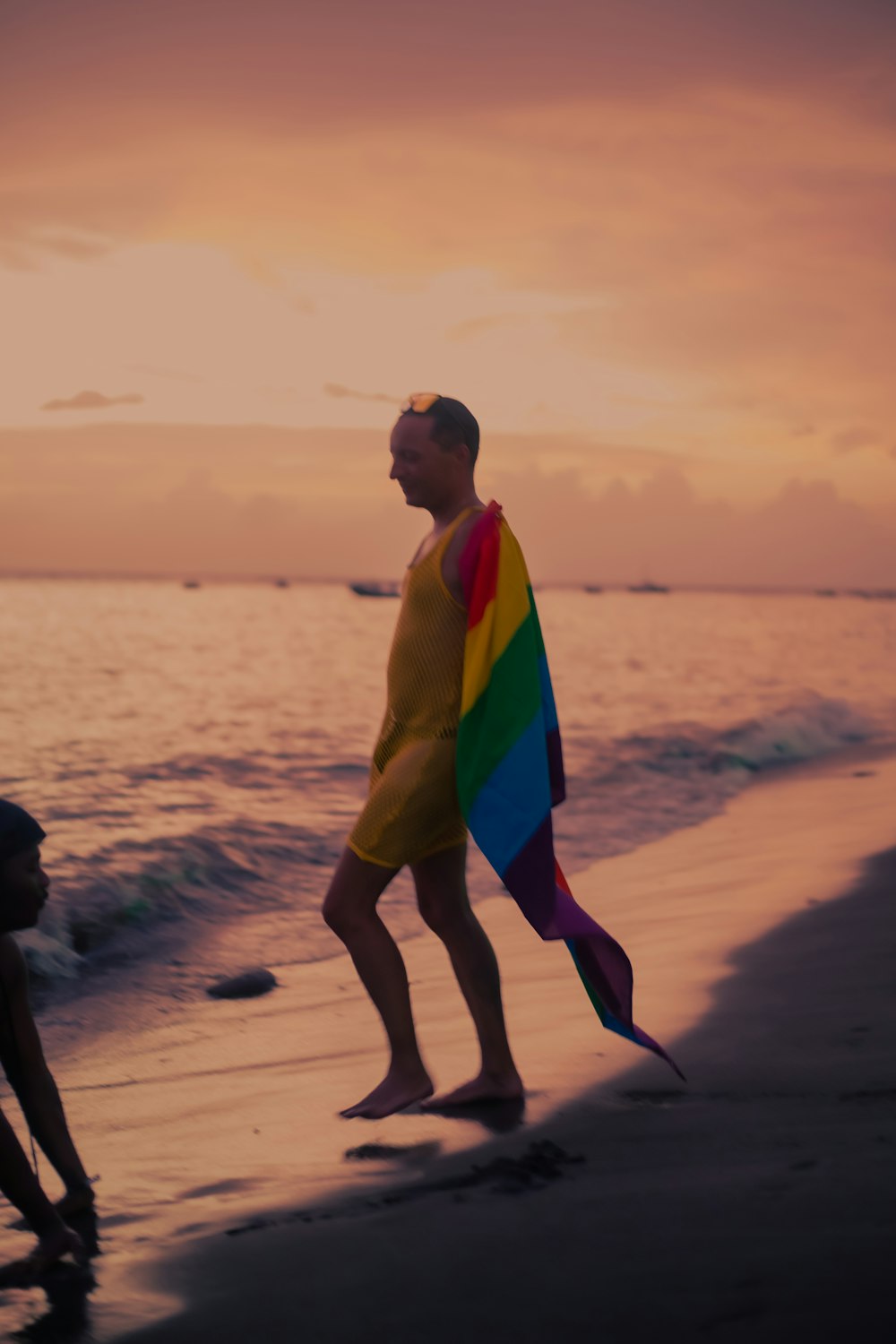 a man holding a rainbow colored kite on the beach