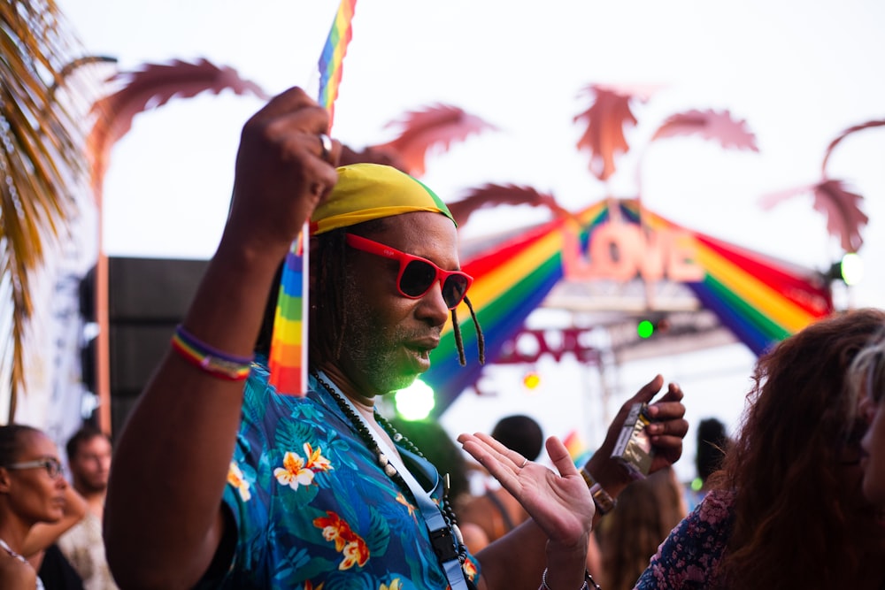 a man in a colorful shirt and sunglasses at a festival