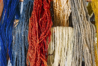 a bunch of different colored yarns hanging on a wall