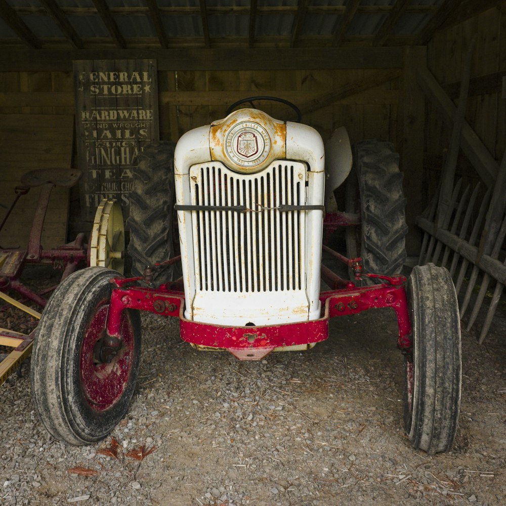 an old red and white tractor parked in a barn