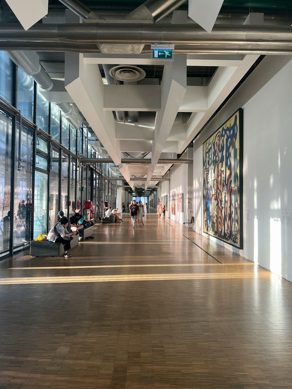 a long hallway with lots of windows and people sitting on benches