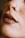 A close-up of a person's nose with a small hoop nose ring and full, matte lips. The skin is covered in freckles.