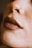A close-up of a person's nose with a small hoop nose ring and full, matte lips. The skin is covered in freckles.