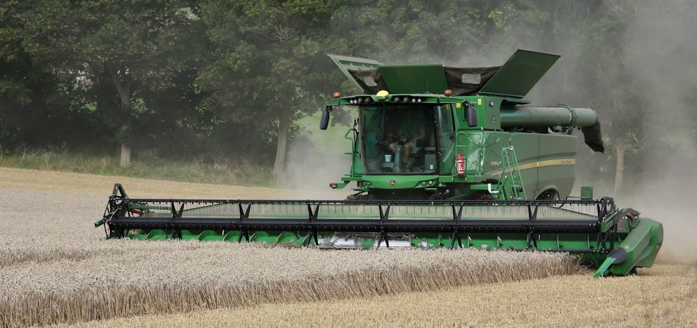 a large green tractor is driving through a field