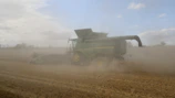 An operator controlling a large agricultural machine during a busy harvest day.