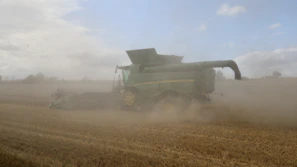 An operator controlling a large agricultural machine during a busy harvest day.