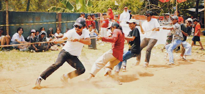 Three distinct tribal groups competing fiercely in a tug-of-war challenge in the forest.