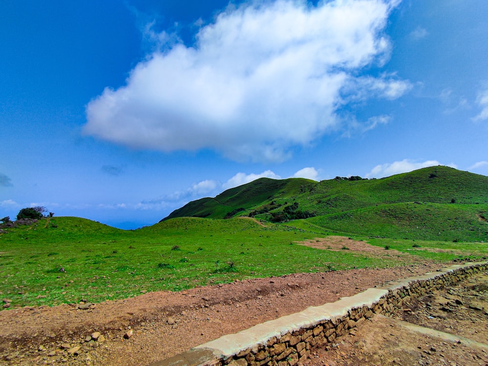 a dirt path leading to a grassy hill