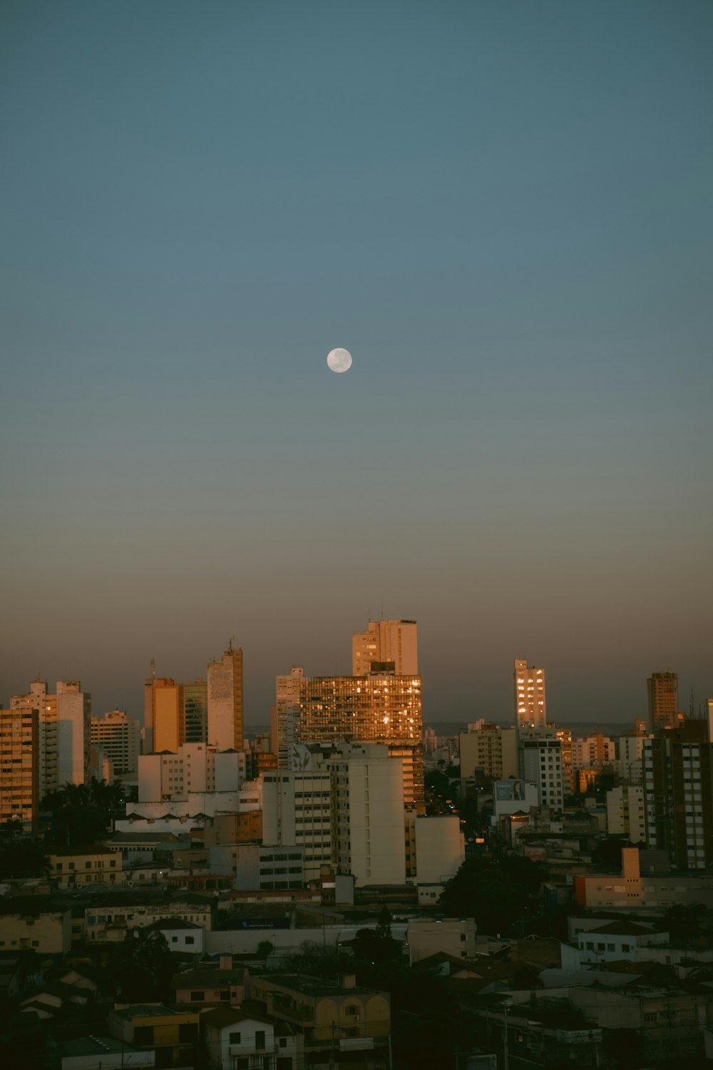 a full moon rising over a city with tall buildings
