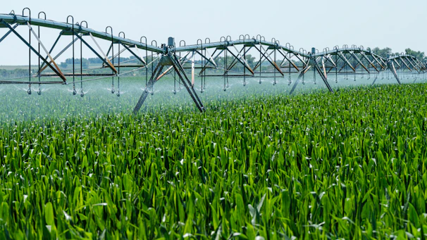 A lush green field being watered by a sprinkler system.