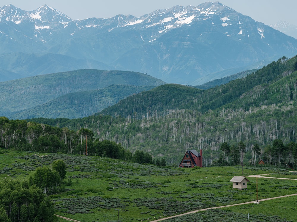 Una casa en medio de un campo con montañas al fondo