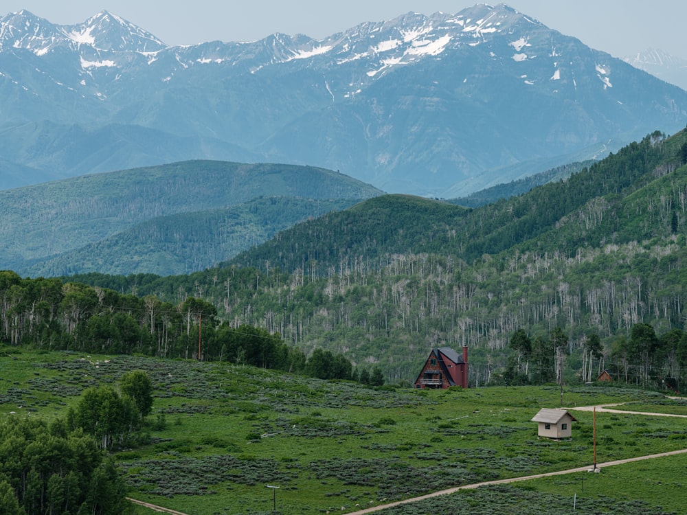 Una casa in mezzo a un campo con le montagne sullo sfondo
