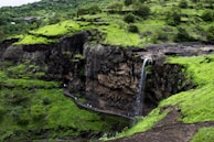 Tourists exploring the lush greenery and waterfalls of a hidden mountain trail.