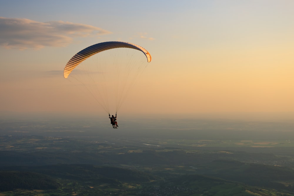 uma pessoa está parasailing no céu ao pôr do sol