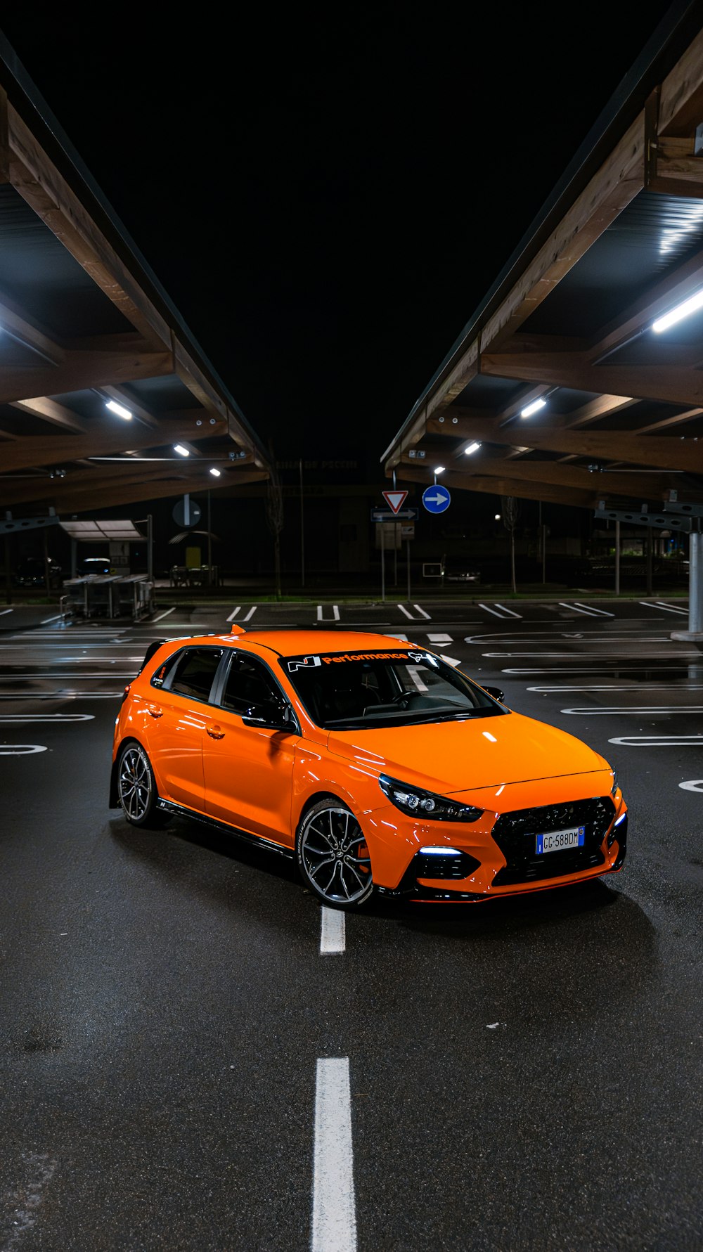 an orange car parked in a parking lot at night