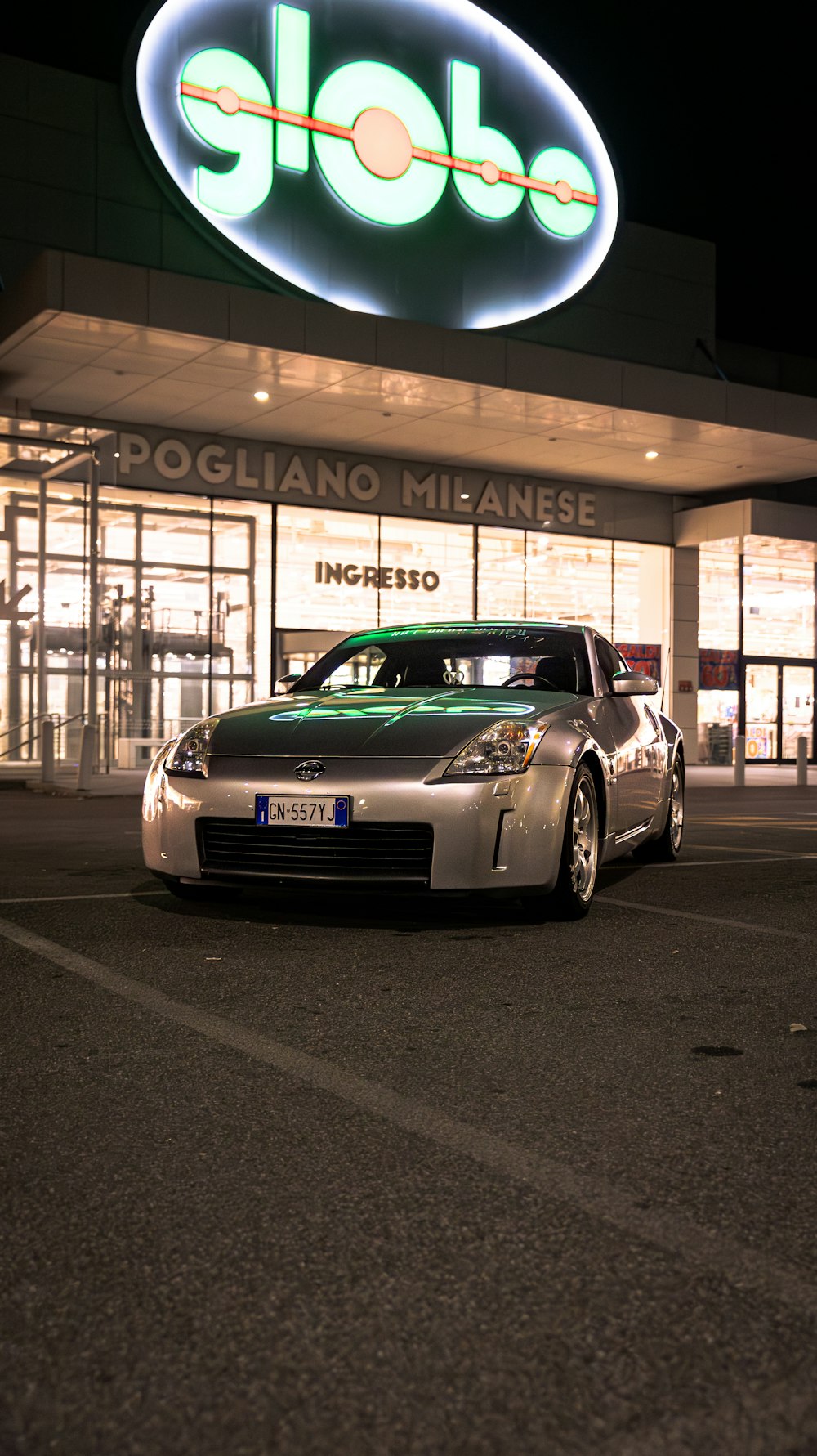 a silver sports car parked in front of a store