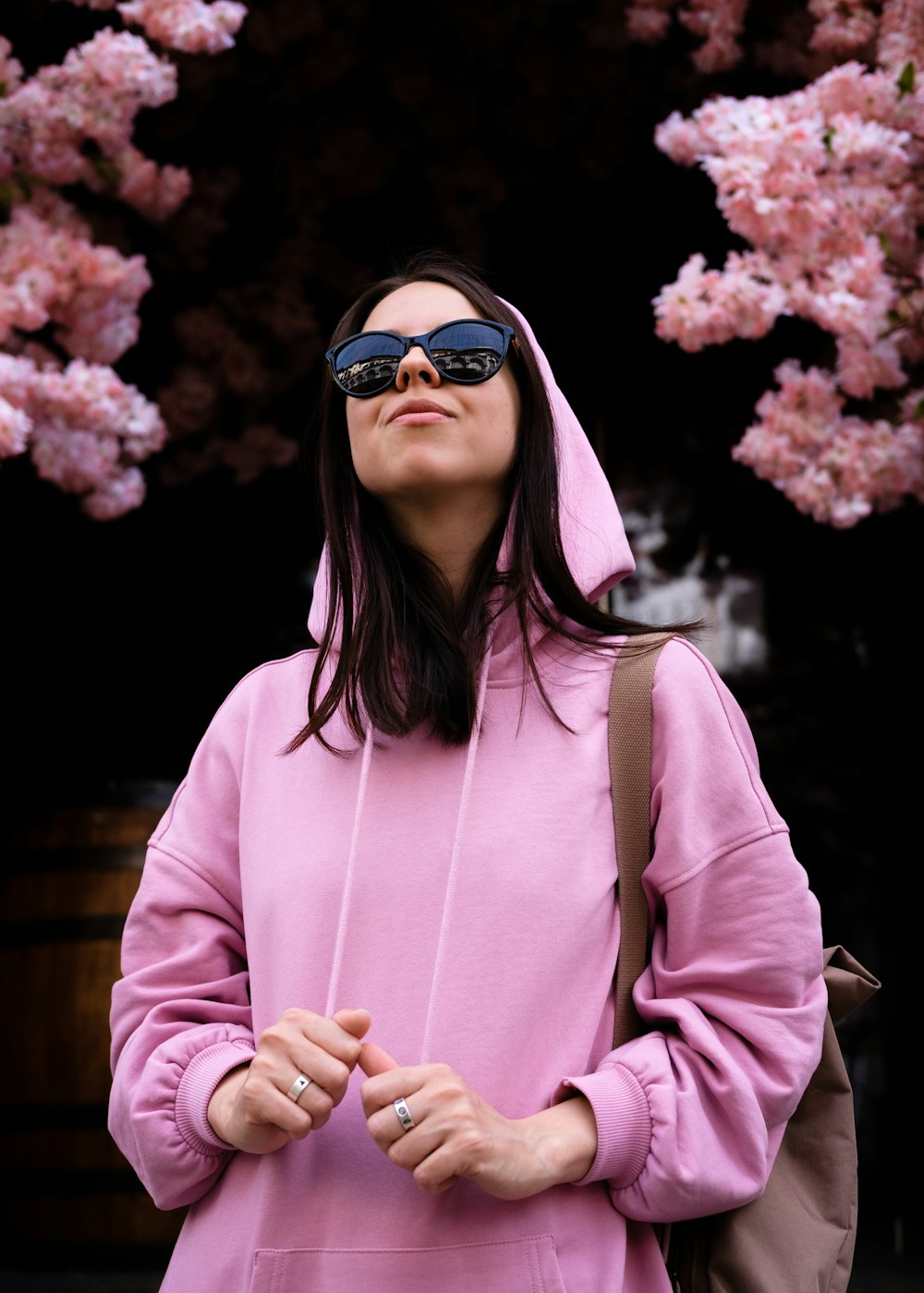 a woman wearing a pink hoodie and sunglasses
