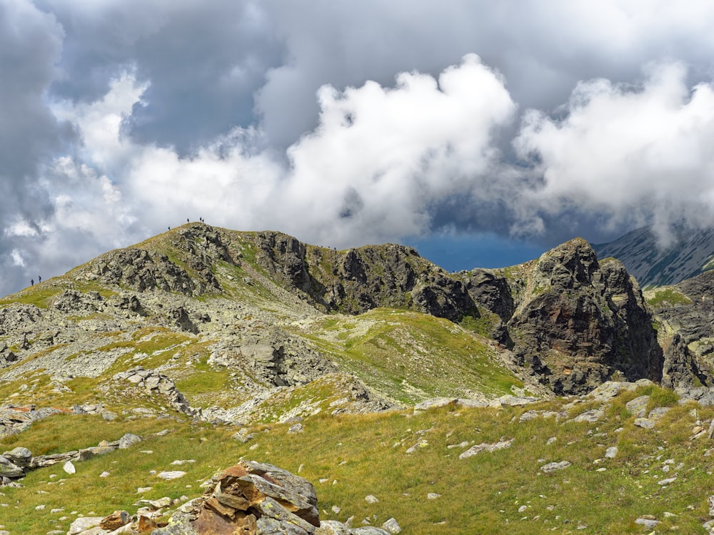 a mountain range with rocks and grass in the foreground